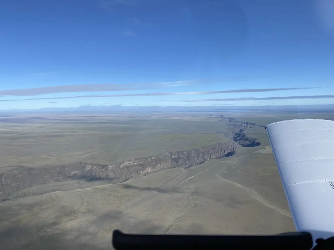 View past the wing strut over desert canyons on a cross-country flight